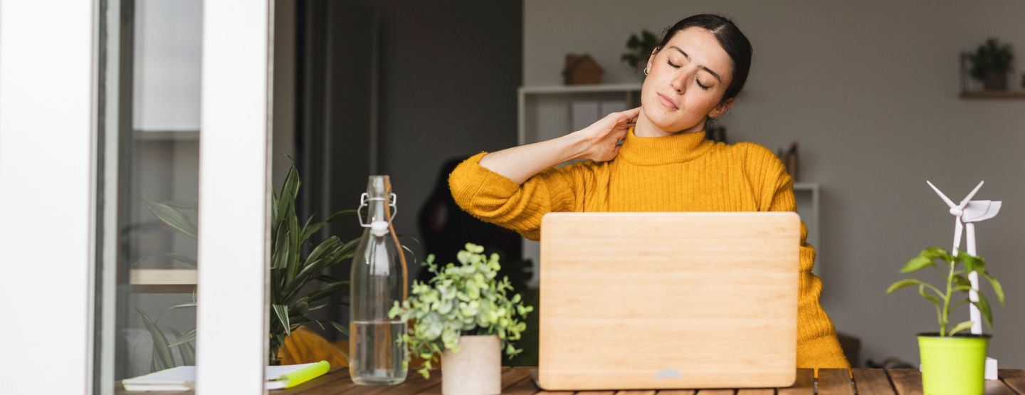 Woman sitting at desk stretches her neck.