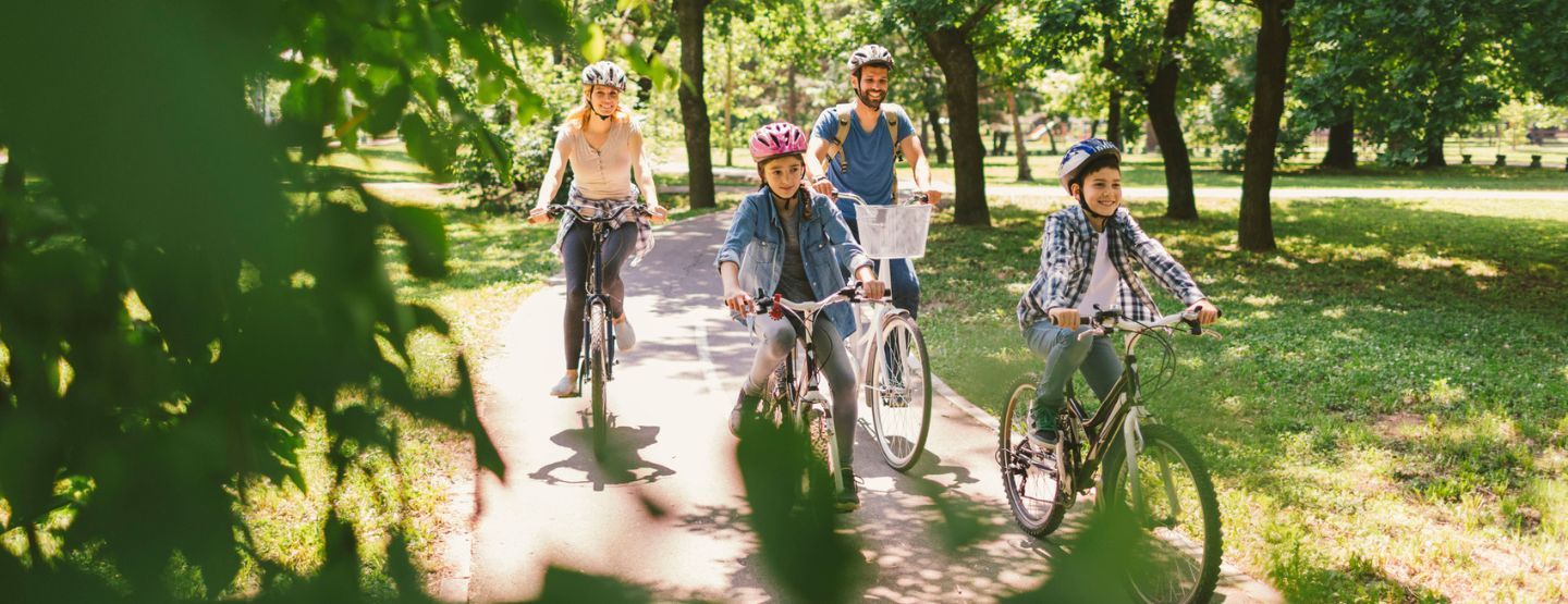 Family riding bikes through park. 