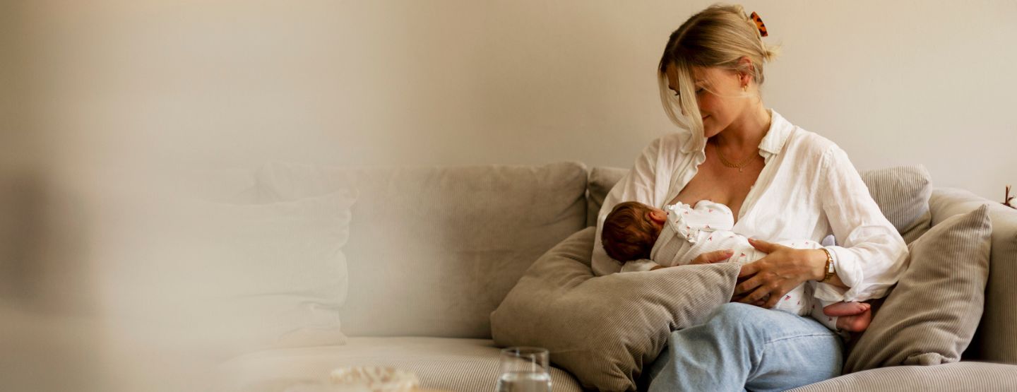 Mother breastfeeding child at home. 