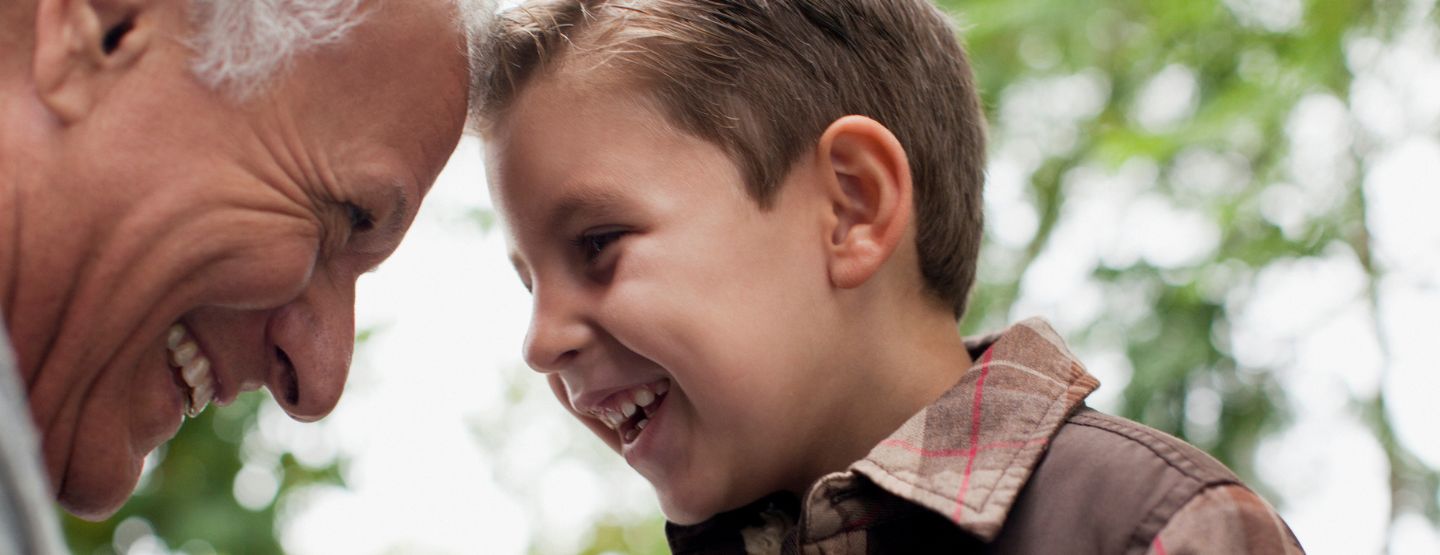 Close up of grandfather and grandson smiling at each other with foreheads touching