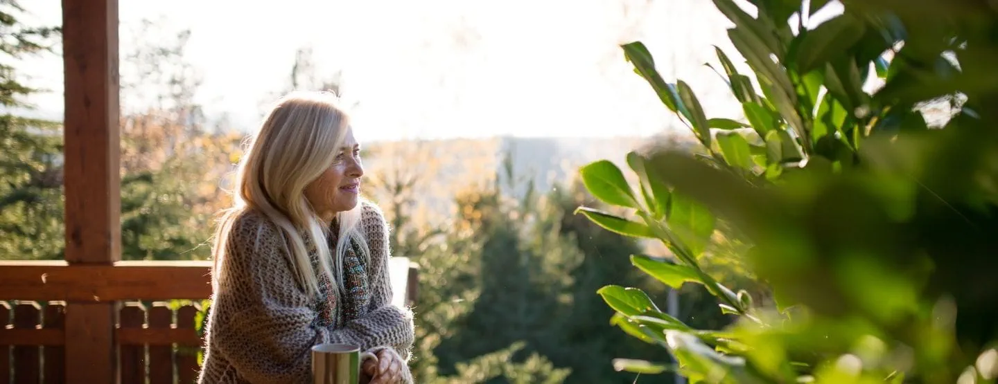 Woman looking out into nature from a deck.