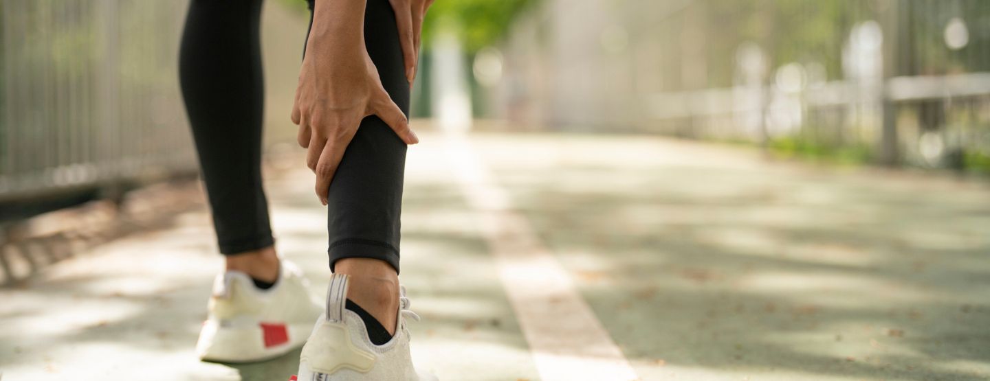 Person gripping calf while walking.