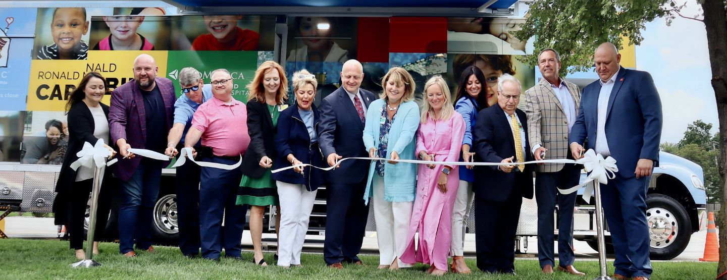 Individuals lined up in front of the new care mobile to cut the ribbon.