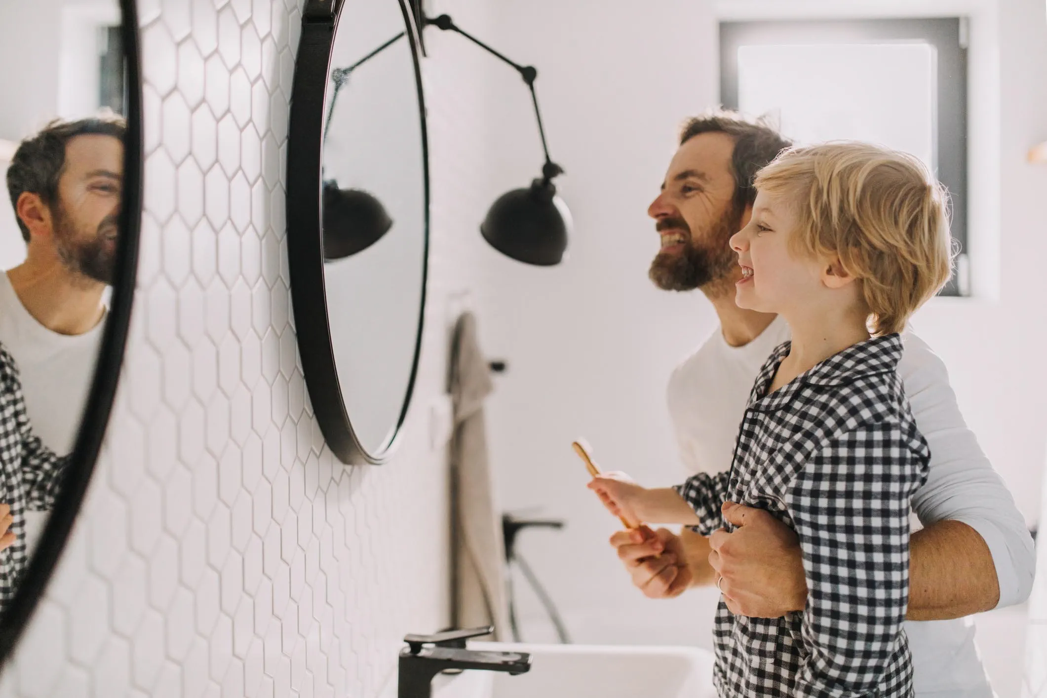 Man with son wearing pajamas in bathroom, morning routine concept.