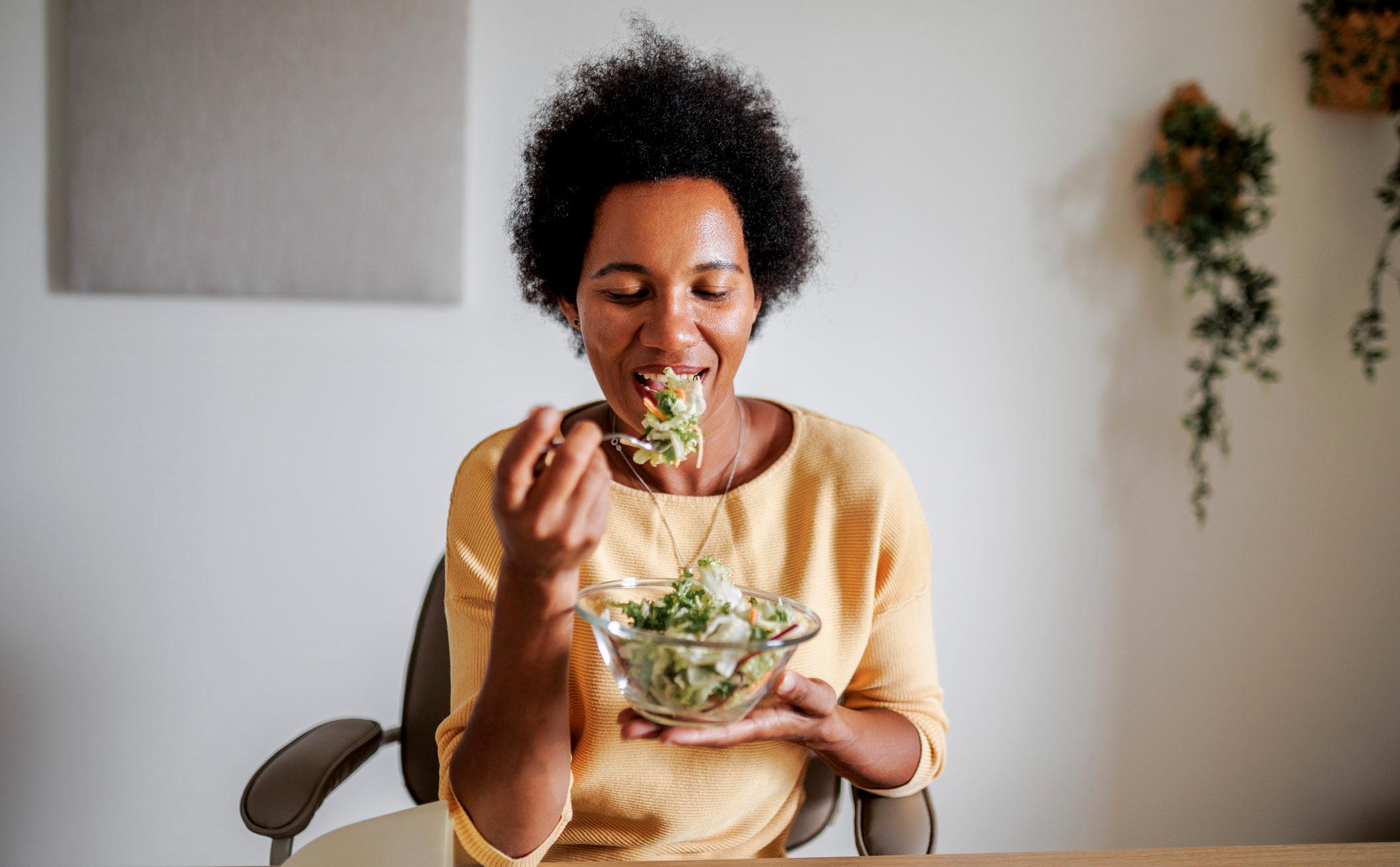 An adult black woman having snack in her home office