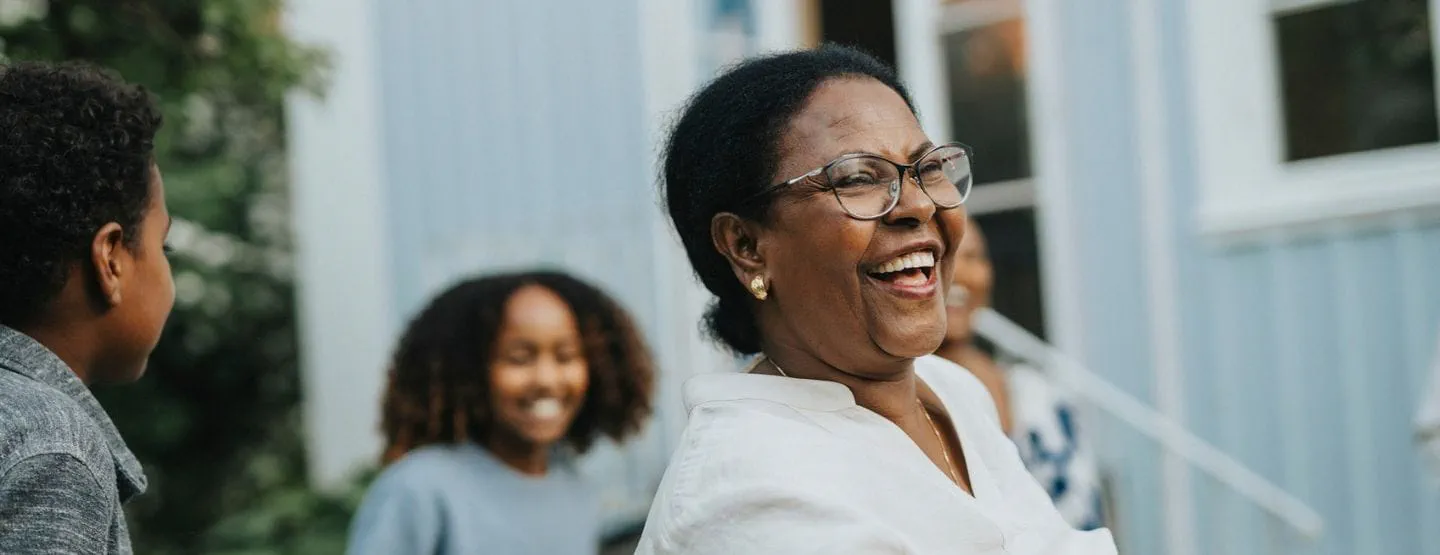 Mature woman wearing glasses smiling with grandkids. 