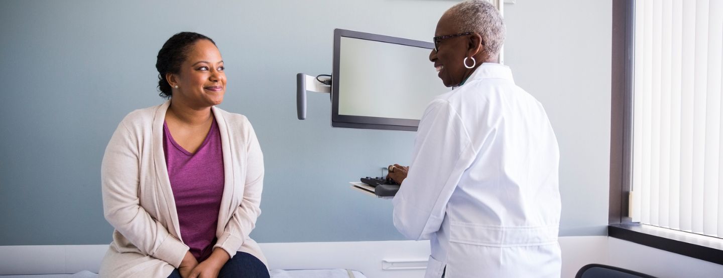 Smiling senior doctor talking to female patient in hospital