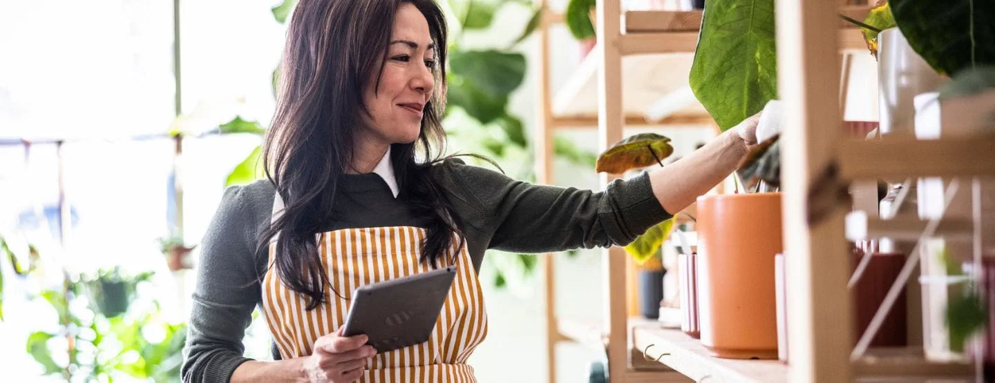 Employee smiling while taking inventory of plants at floral shop. 