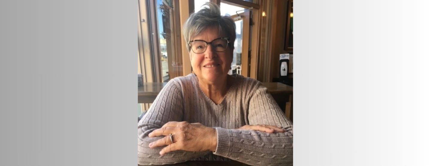 Judy sitting down at table, smiling at the camera.