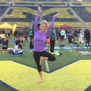 Kelli Meeks smiling at the camera while doing a yoga pose.