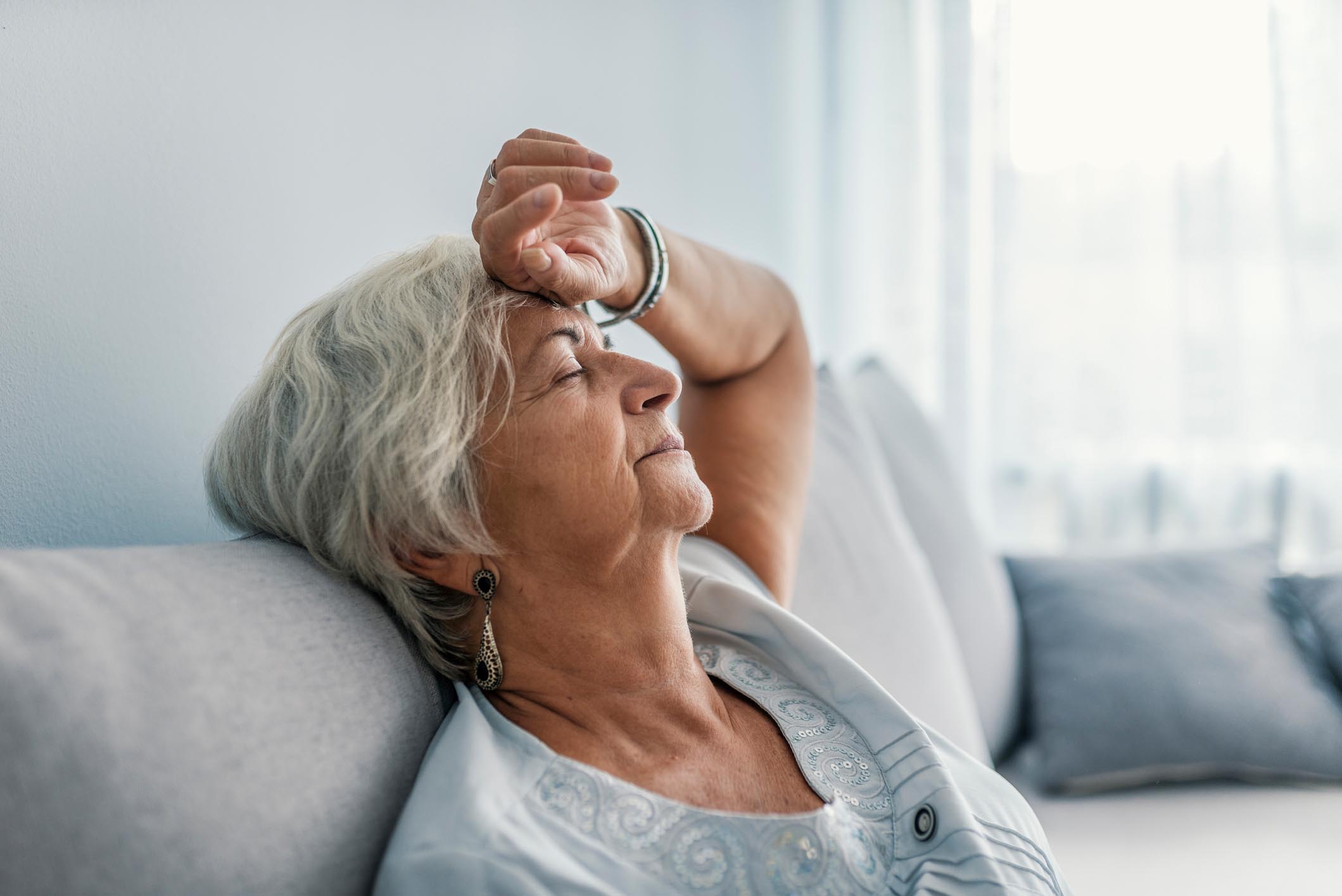 Thoughtful senior woman relaxing on bed.
