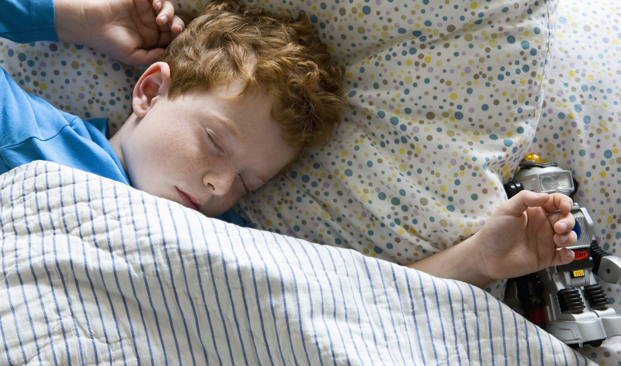A little boy sleeping in a bed.