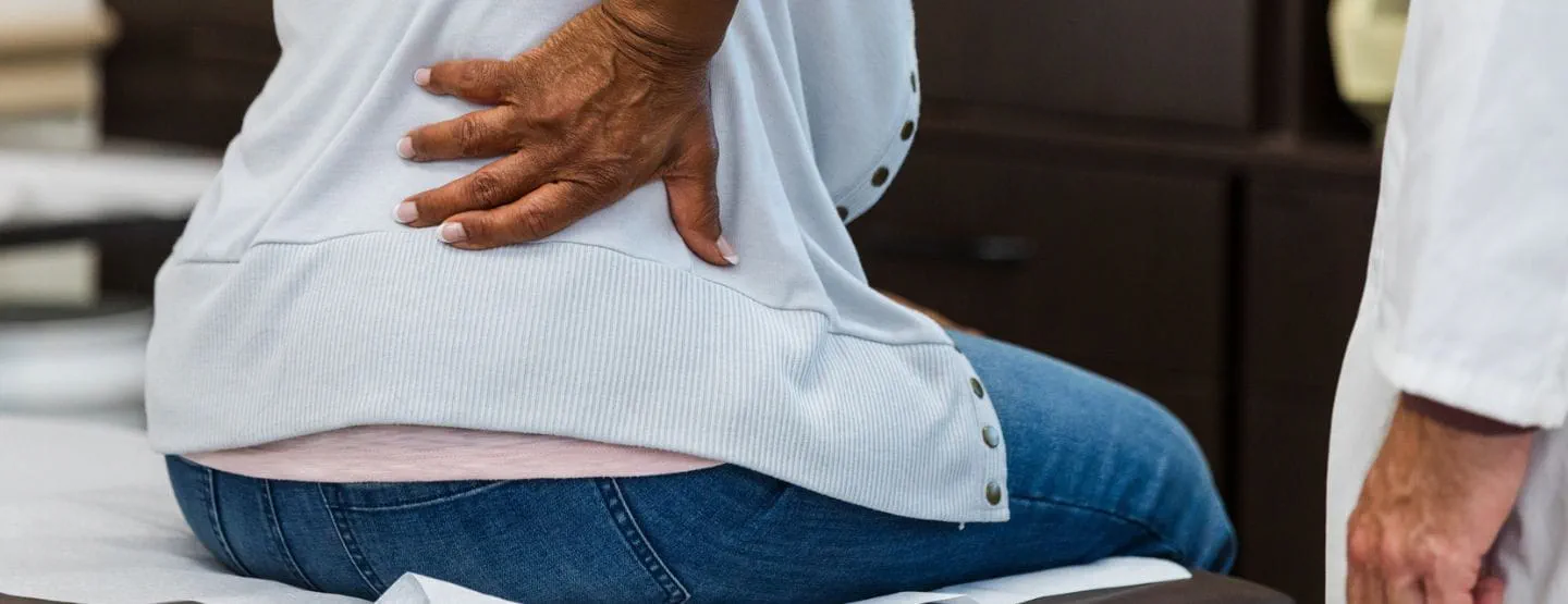 Women touches her lower back during an exam at the doctor's office