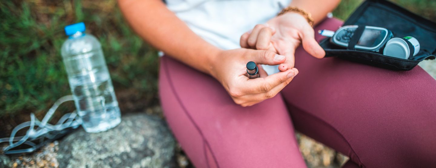 Active woman checking blood sugar while outside.