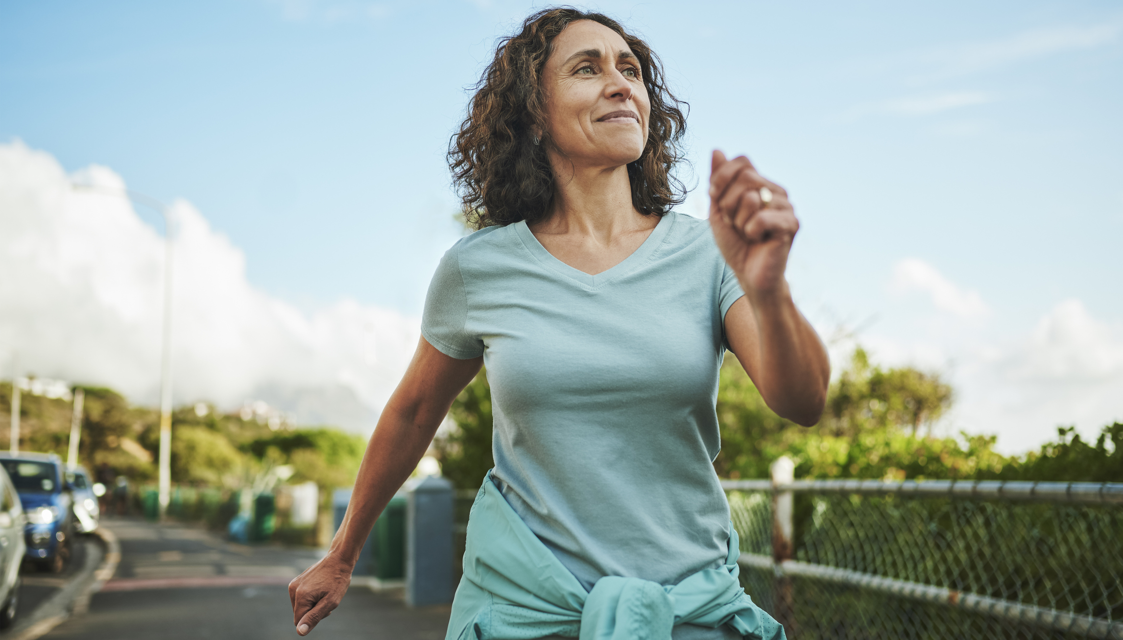Smiling mature woman out for a power walk in summer