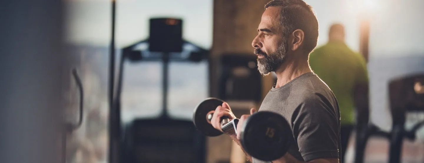 Older man in gym lifting free weights.