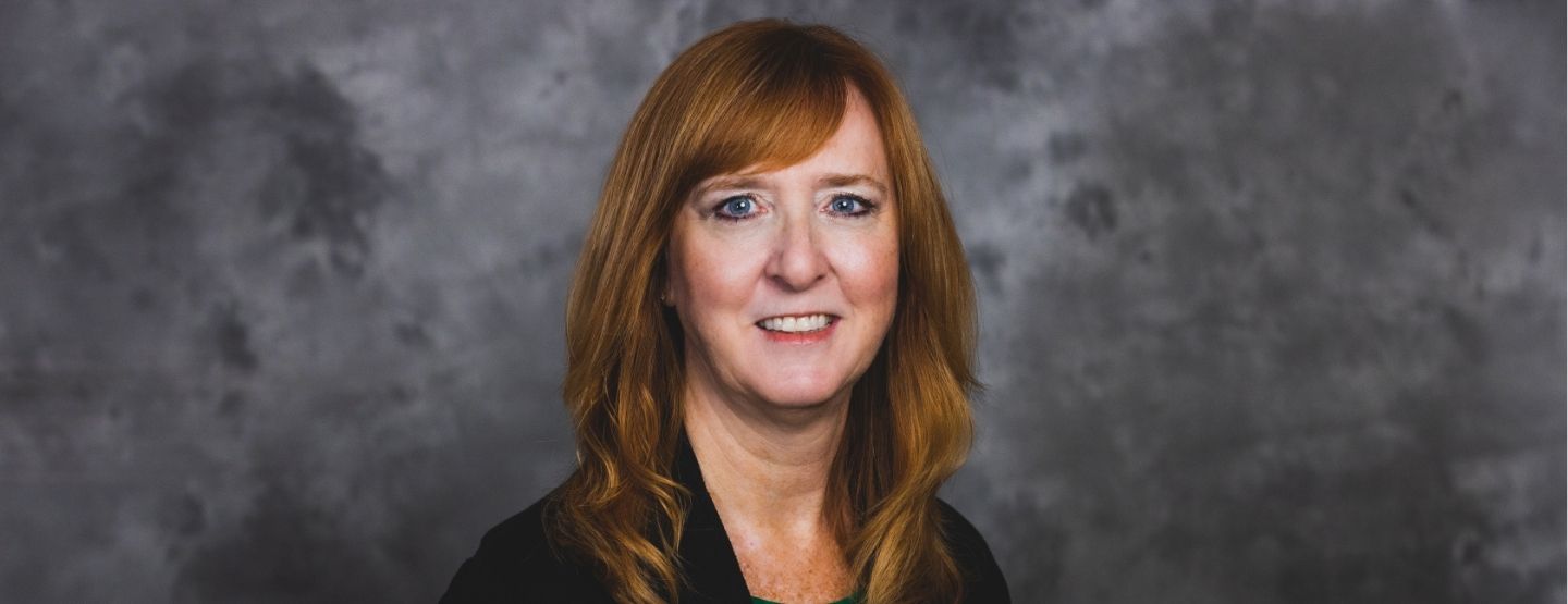 Headshot of Paula Grieb against a dark grey background
