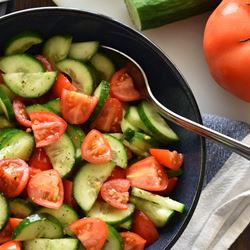 Bowl full of chopped cucumbers and tomatoes.