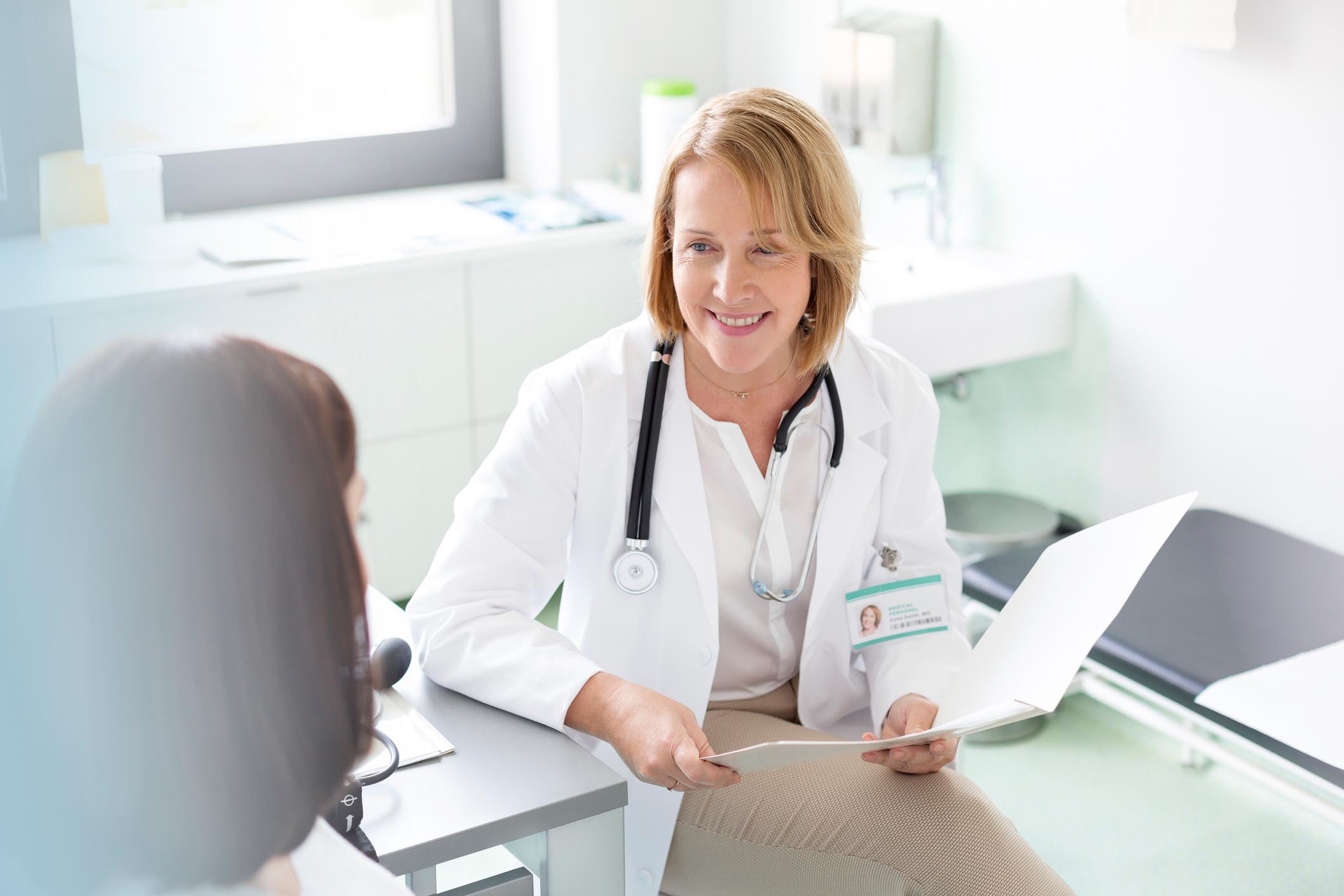 A smiling female doctor meets with a female patient.