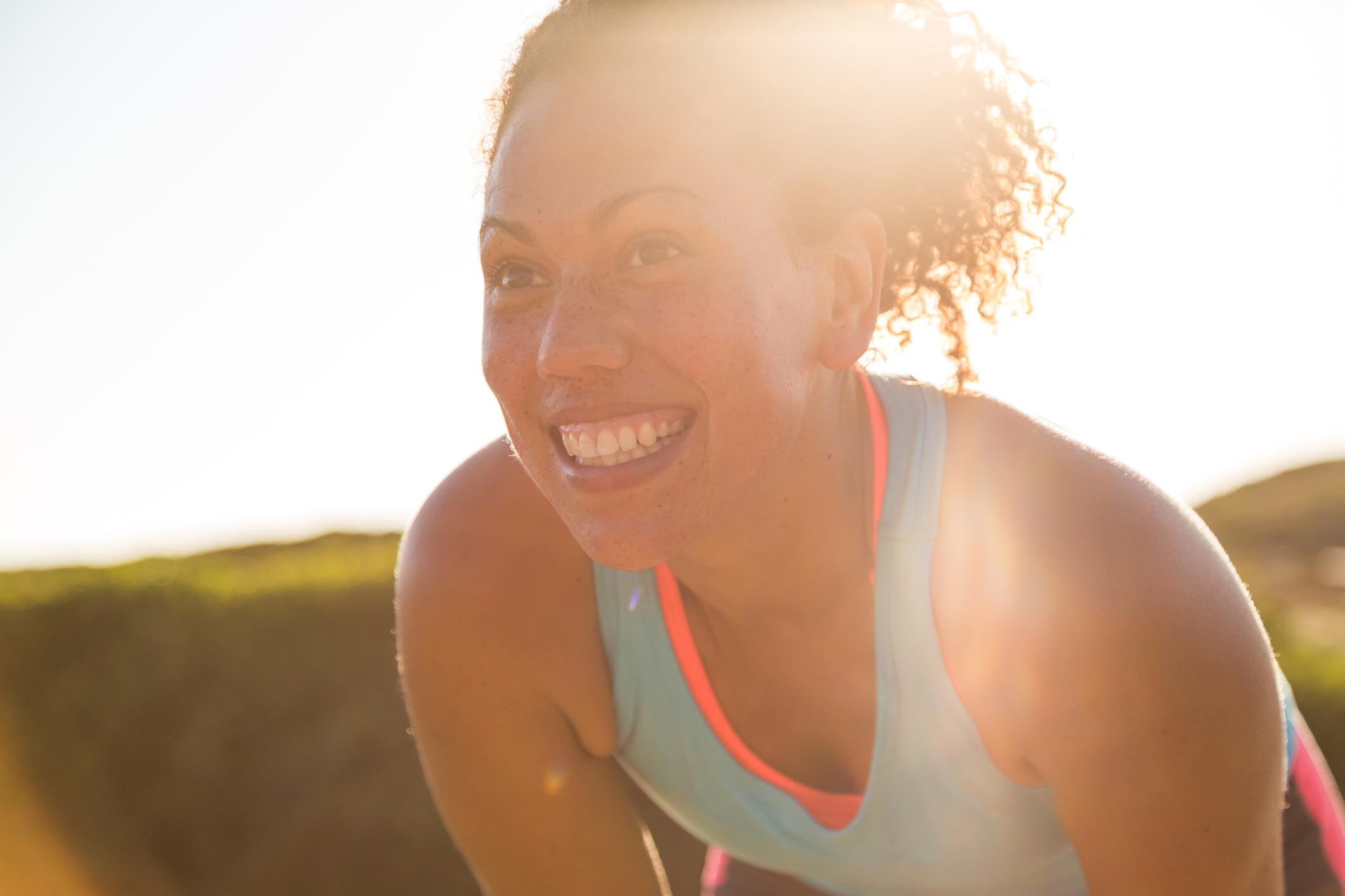 A smiling woman rests after exercising outdoors.