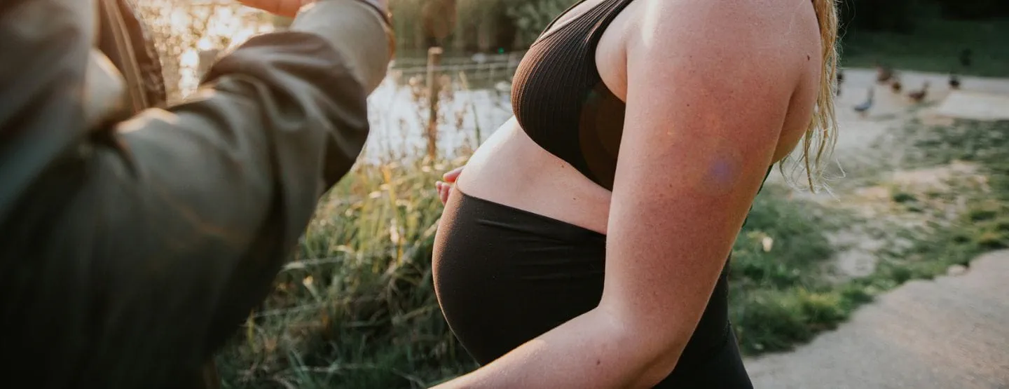 Pregnant woman standing outside.