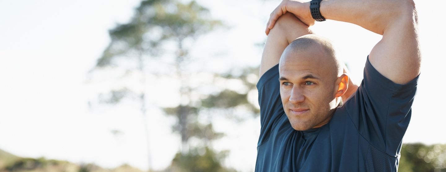 Middle aged man stretching his triceps. 