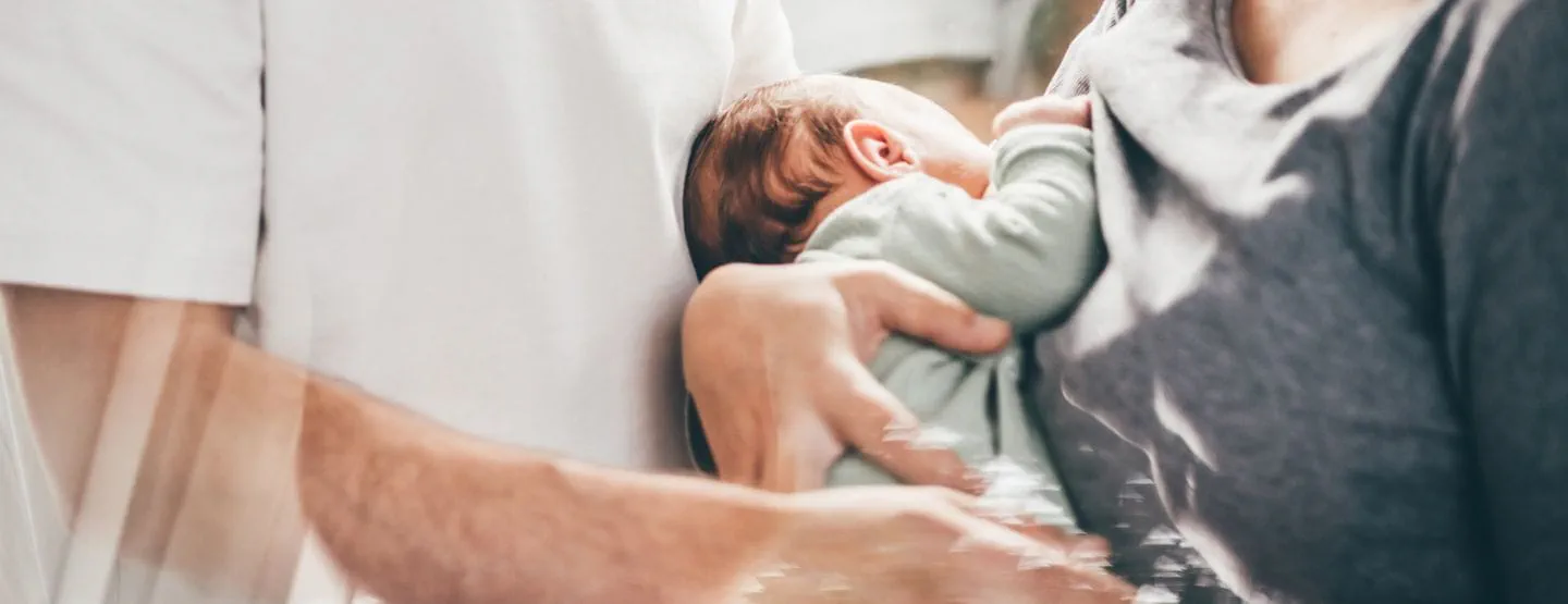 New mom holds baby with dad. 