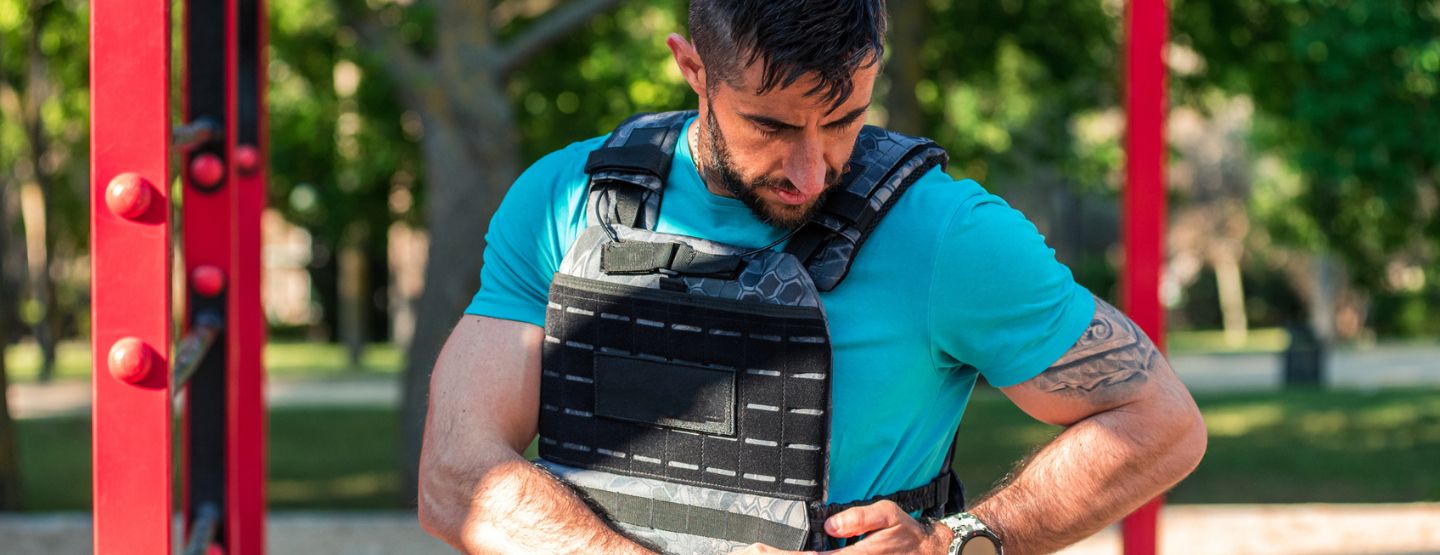 Man adjusting straps on weighted vest before workout. 