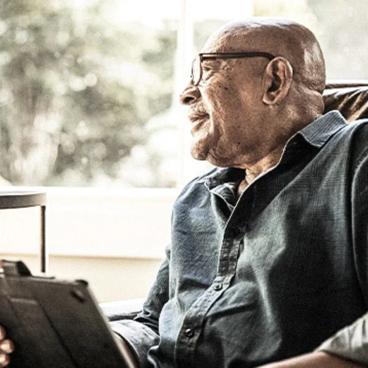 Elderly man looks at clinical trials and research projects on his tablet