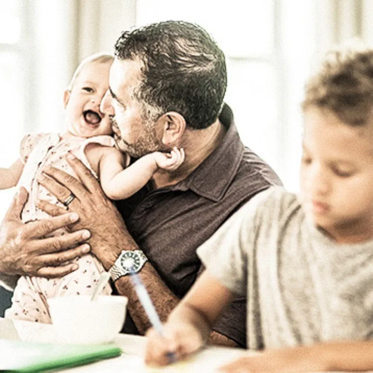 A man sits at the table with his toddler and preschooler as he considers genetic therapy