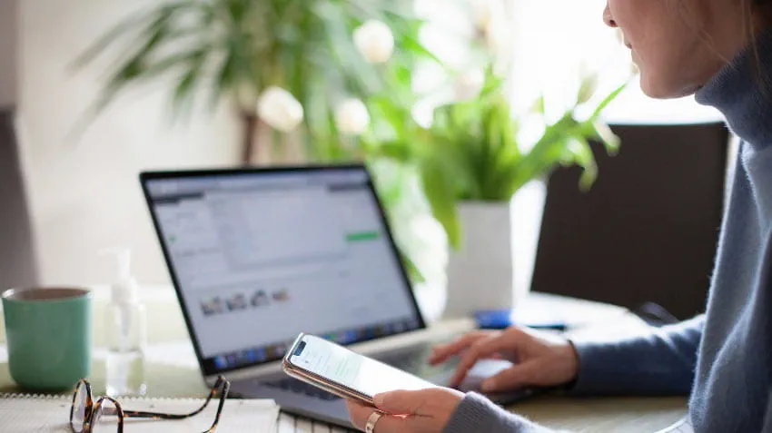 View from the side of a woman on her laptop and mobile phone.
