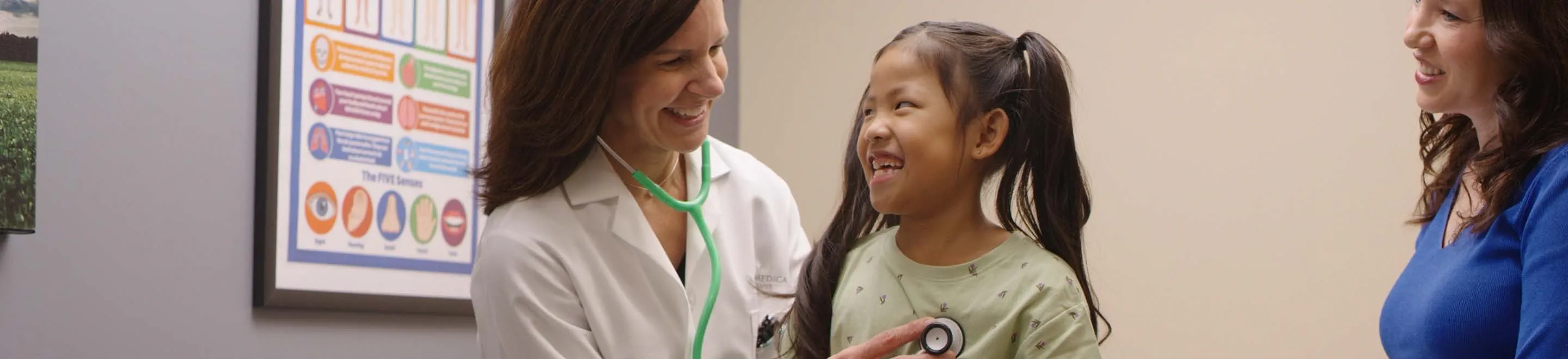 a ProMedica physician check's a young patient's heartbeat with a stethoscope as the patient's mother looks on