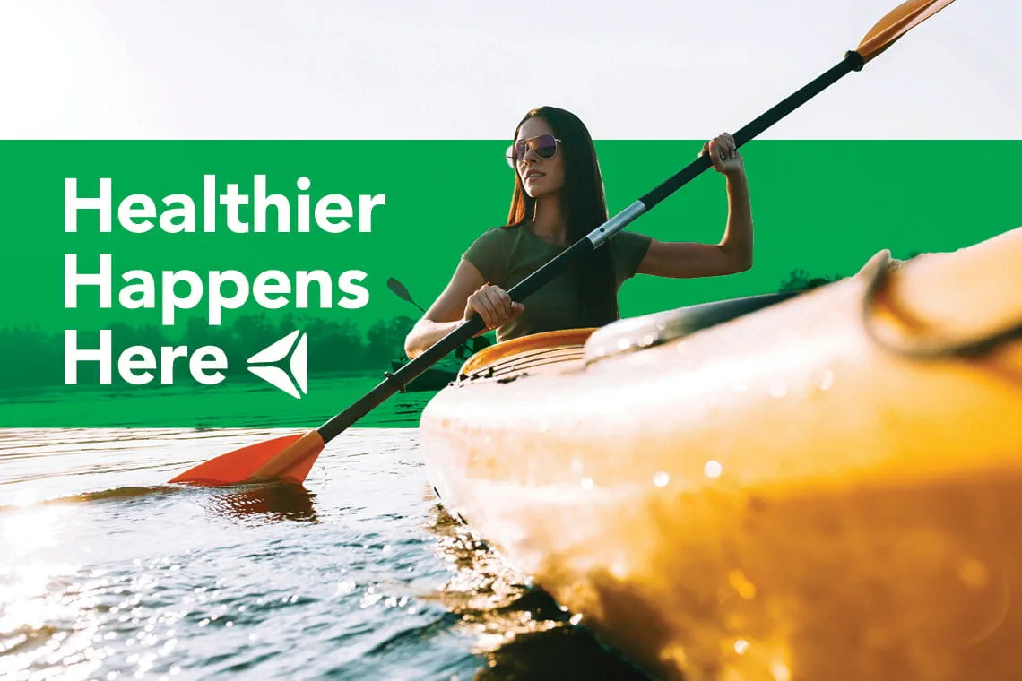 A woman kayaks on a lake. Overlay text reads "Healthier Happens Here."