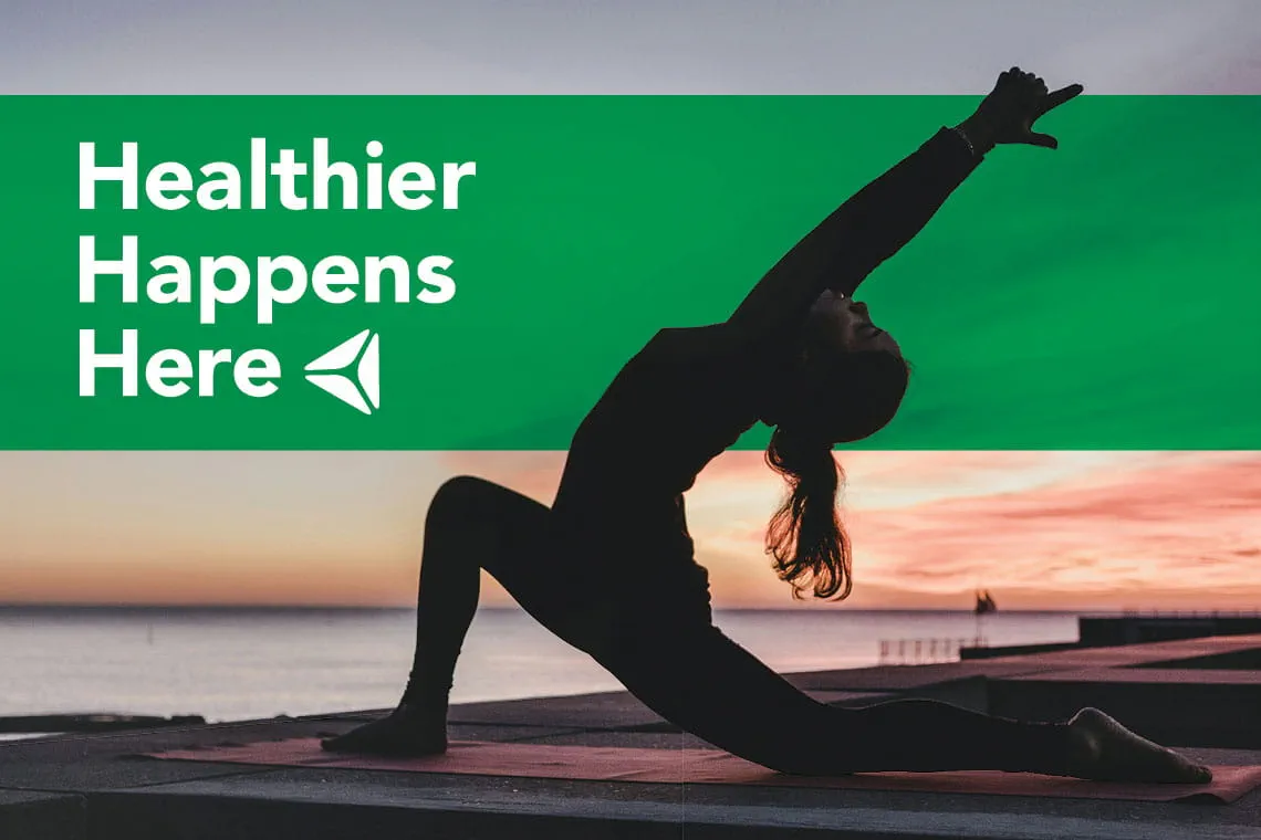 A woman does yoga at sunrise. Overlay text reads "Healthier Happens Here."