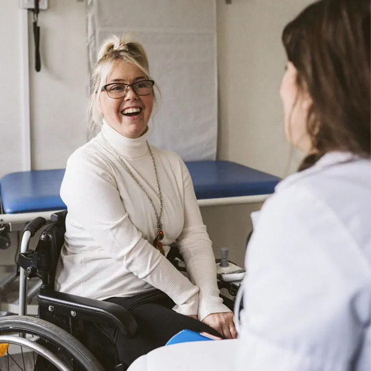 a smiling female patient using a wheelchair has an appointment with her physician