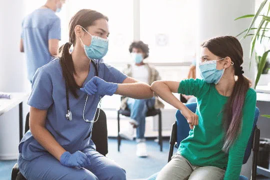 A young female nurse bumps elbows with a preteen girl at a ProMedica facility