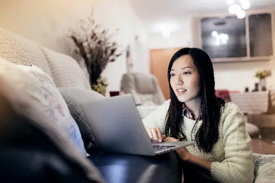 A young woman at home uses her laptop to check social media for public health updates