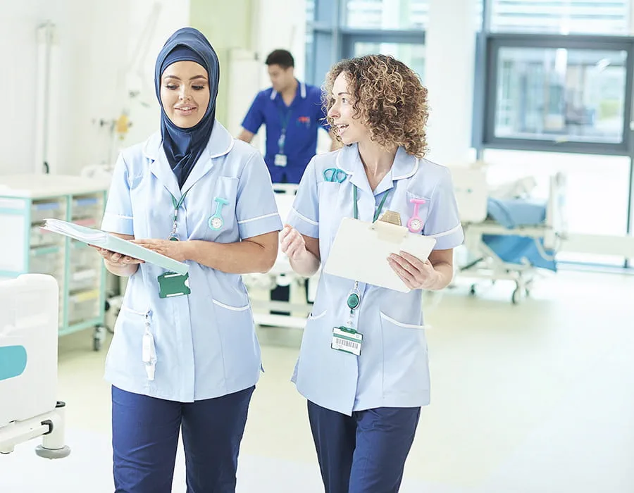 Two nurses discuss scholarship opportunities while walking in a hospital ward