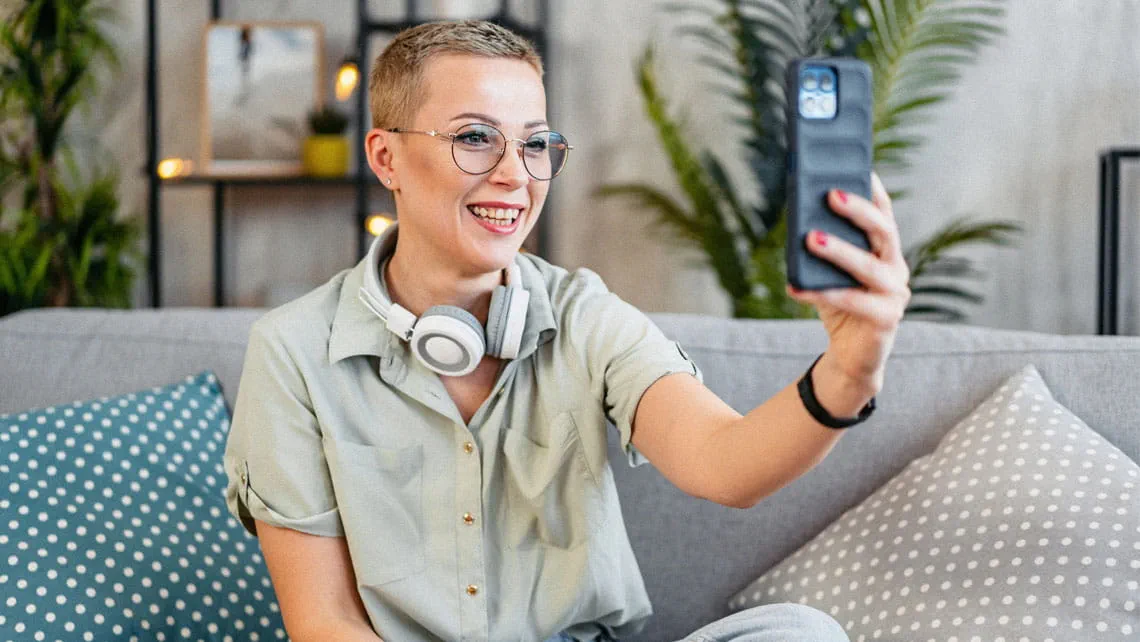 a young woman uses her phone at home on a video call