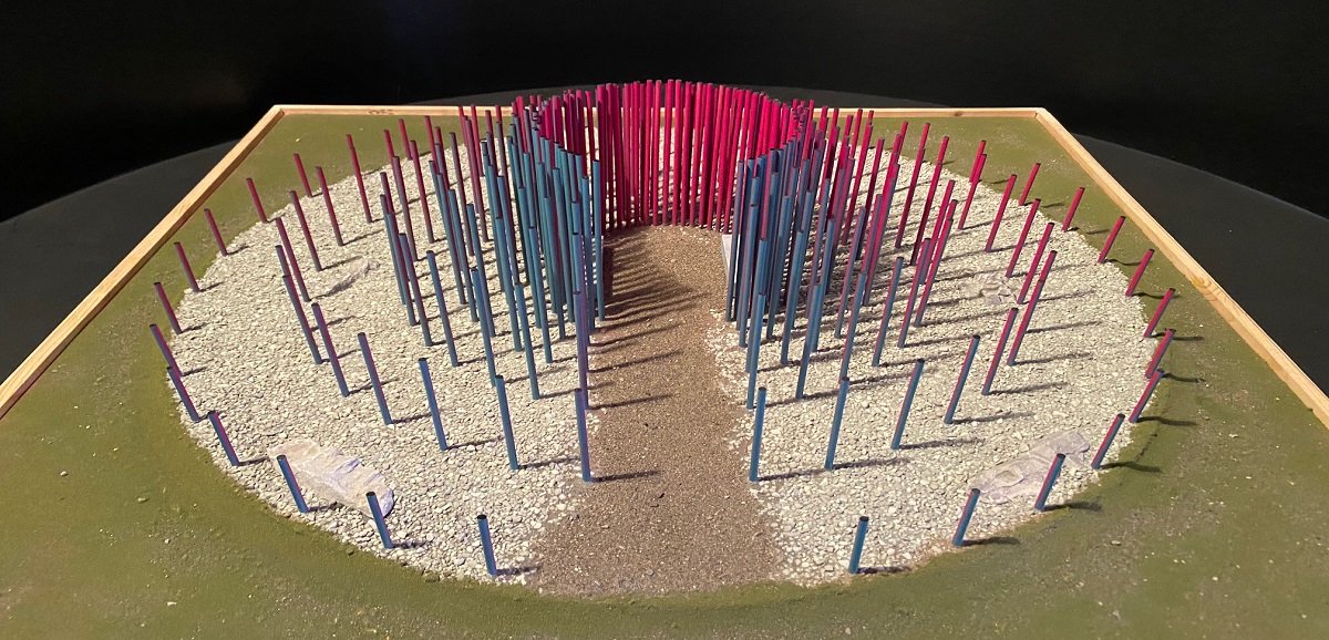 An outdoor art display using blue and red pipes in a circular design with a path in middle.
