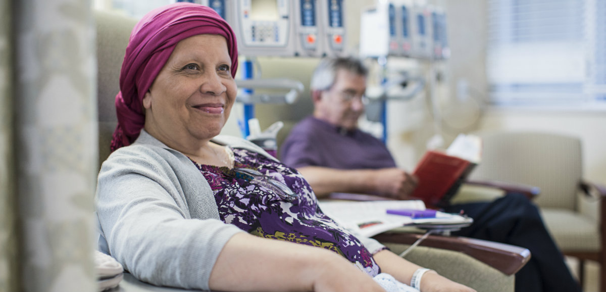 A senior female cancer patient sitting in a chair while going through cancer treatment.