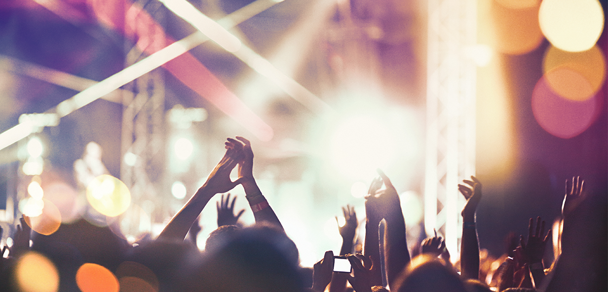A shot of the audience with their arms in the air at a concert.