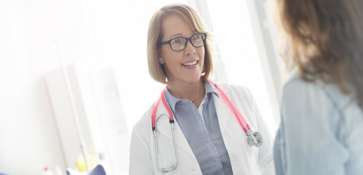 A female physician meets with a female patient in a hospital exam room.