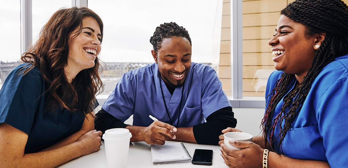 A small group of nurses sitting at a table and laughing together.