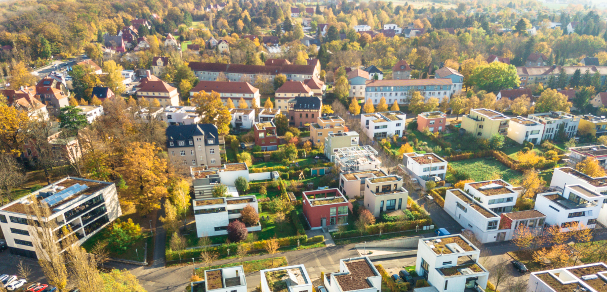 An aerial view of a town with tree lined streets, homes, apartments, and buildings.