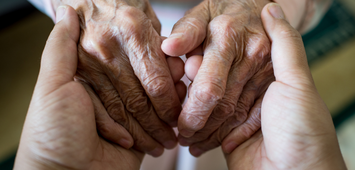 A close up of a younger and an older person holding hands