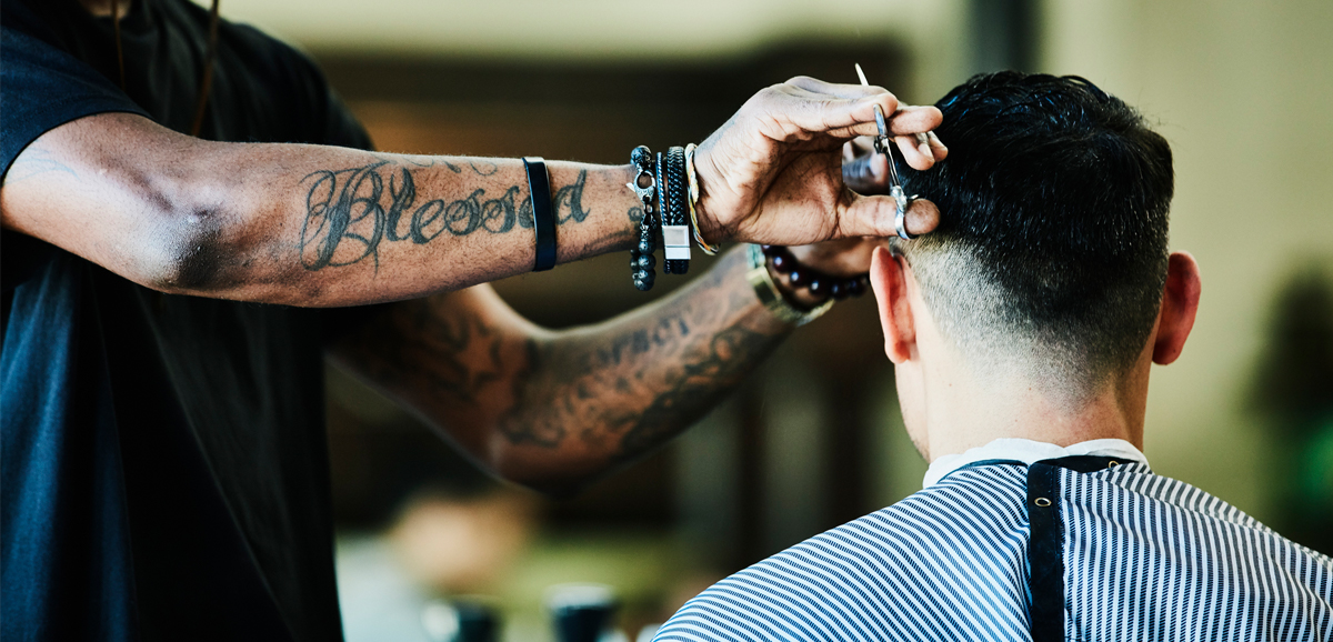 A male barber giving a haircut to a male client 