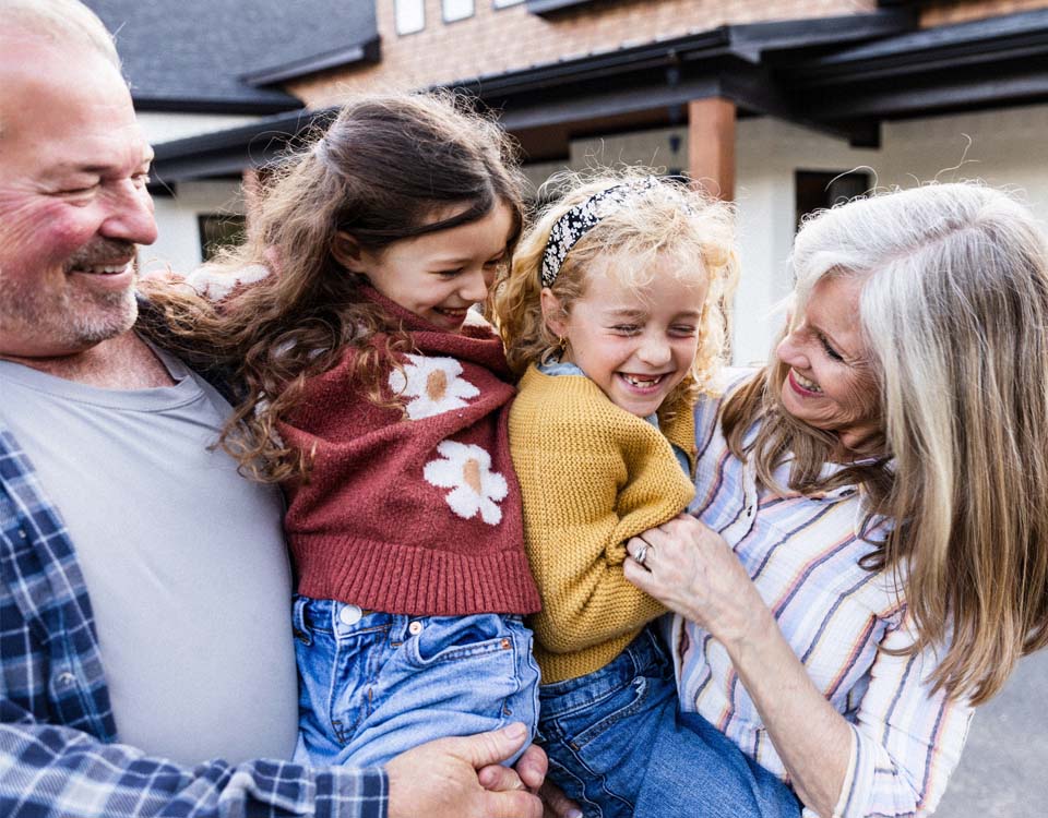 grandparents hug their two school-aged granddaughters