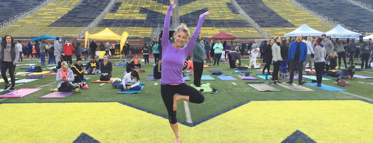 Woman smiling at the camera while doing a yoga pose.