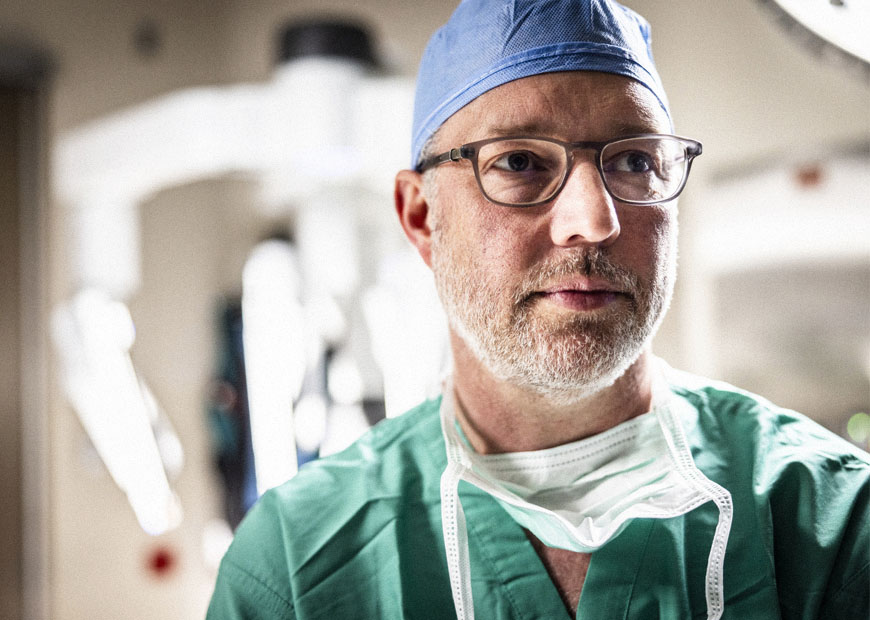 a surgeon stands in the operating room with a surgical robot visible in the background